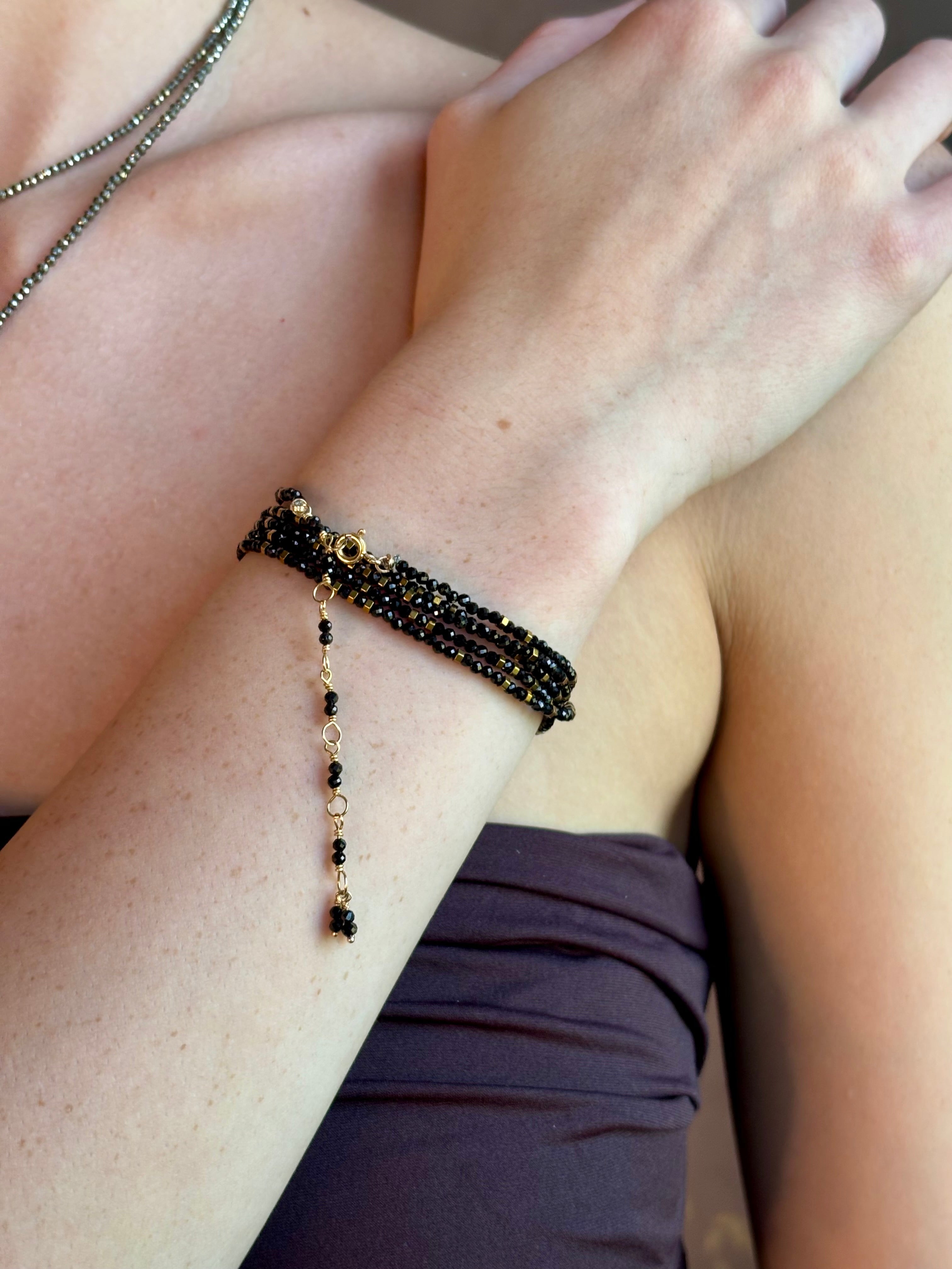 Woman wearing spinel confetti wrap Bracelet from Canadian fine jewelry artist Anne Sportun with natural stone spinel and 18k yellow gold beads that can double as a necklace perfect for travel