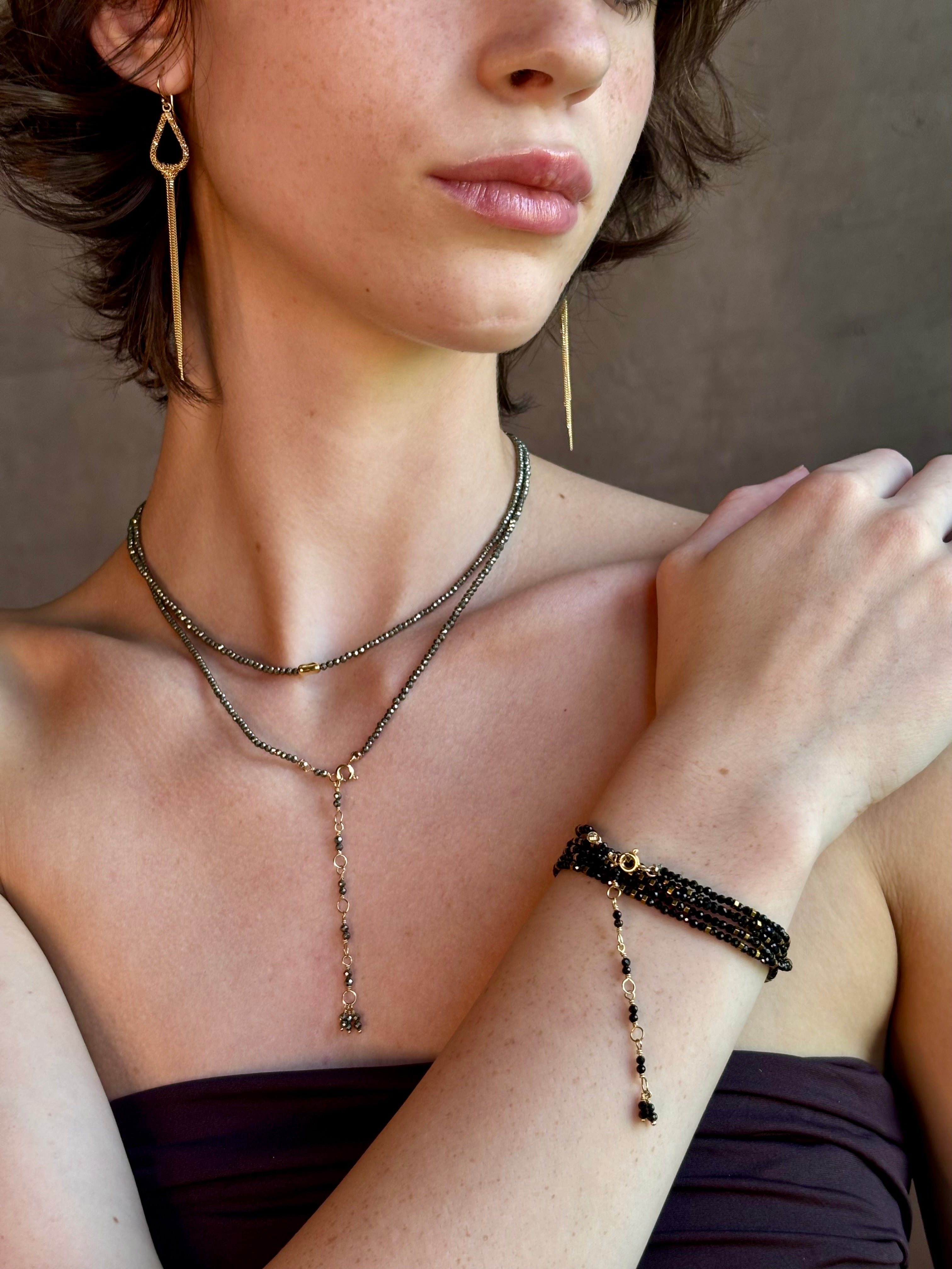 Woman wearing spinel confetti wrap Bracelet from Canadian fine jewelry artist Anne Sportun with natural stone spinel and 18k yellow gold beads that can double as a necklace perfect for travel