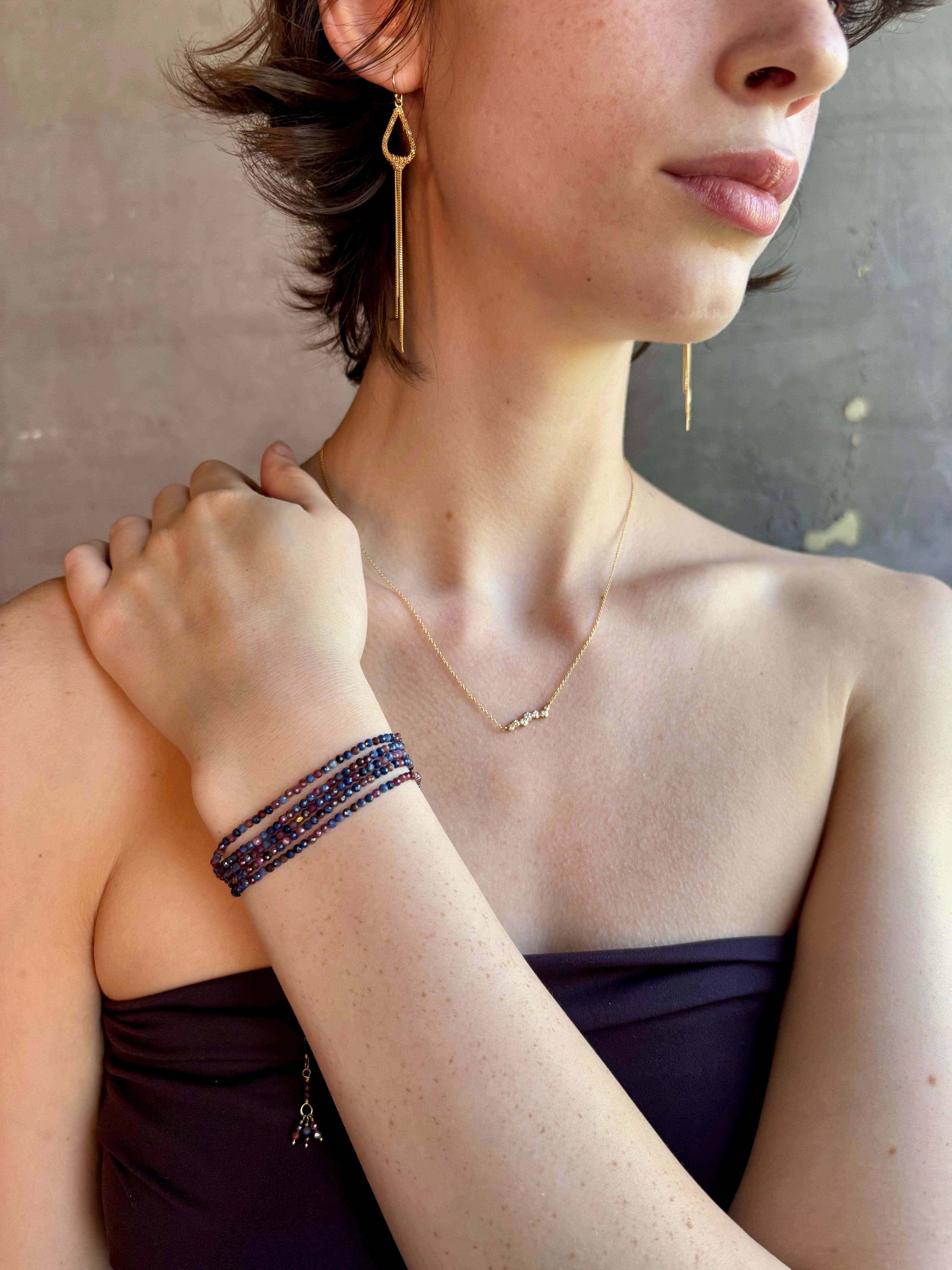 Woman wearing sapphire wrap Bracelet from Canadian fine jewelry artist Anne Sportun with natural multi-colored sapphires and 18k yellow gold that can double as a necklace perfect for travel