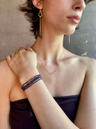 Woman wearing sapphire wrap Bracelet from Canadian fine jewelry artist Anne Sportun with natural multi-colored sapphires and 18k yellow gold that can double as a necklace perfect for travel