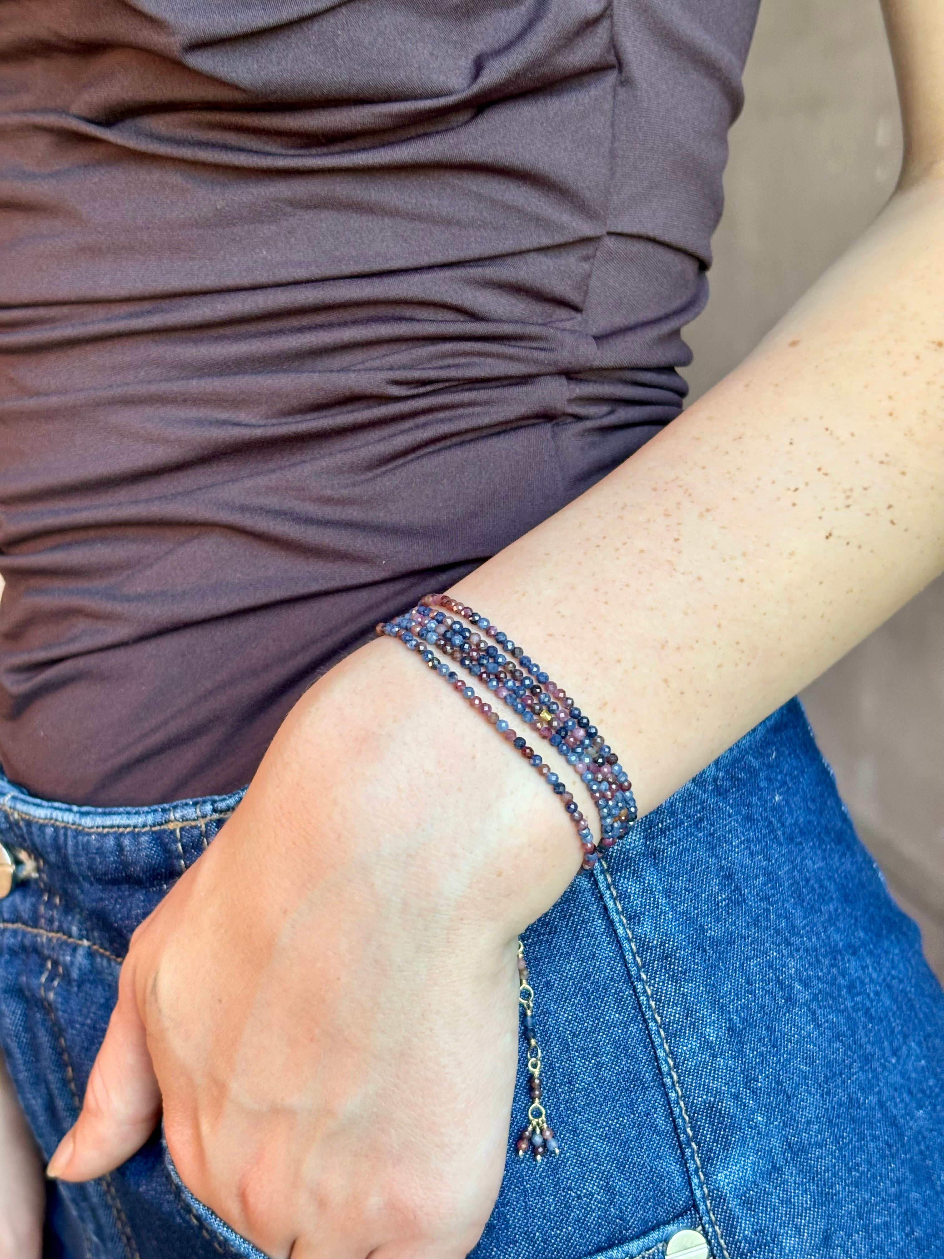 Woman wearing sapphire wrap Bracelet from Canadian fine jewelry artist Anne Sportun with natural multi-colored sapphires and 18k yellow gold that can double as a necklace perfect for travel