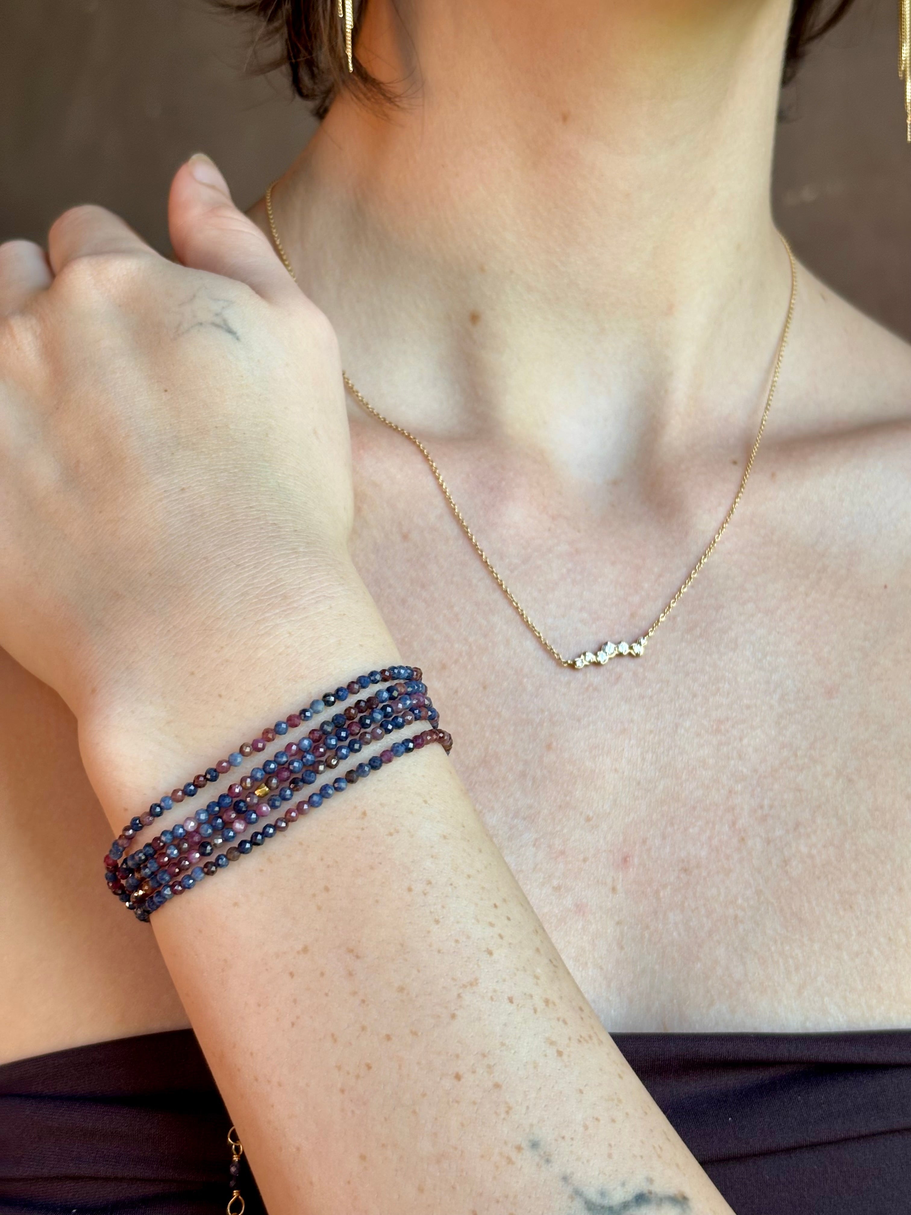Woman wearing sapphire wrap Bracelet from Canadian fine jewelry artist Anne Sportun with natural multi-colored sapphires and 18k yellow gold that can double as a necklace perfect for travel