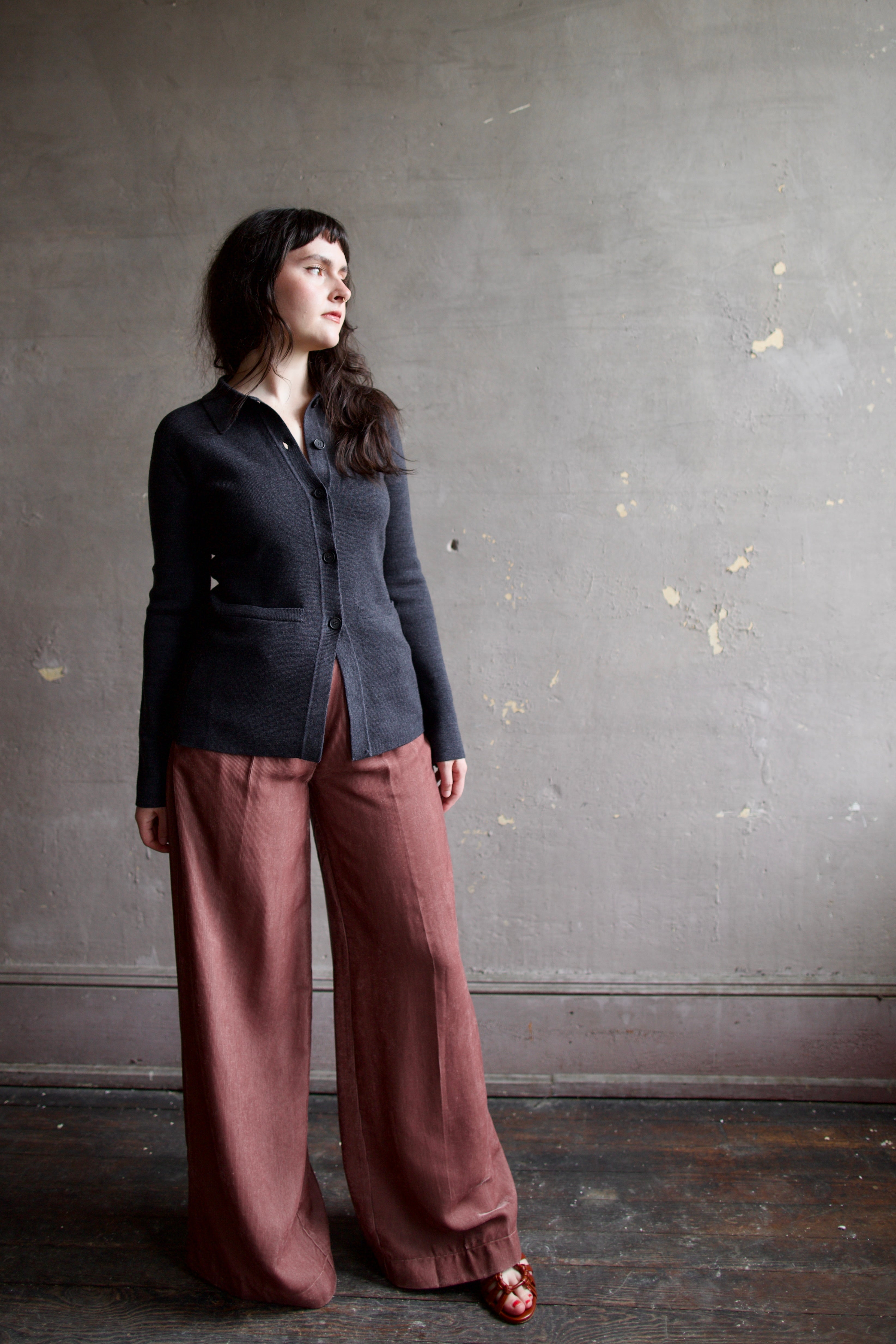 Model wearing Apiece Apart Betti dark gray knit cardigan with a button front, long sleeve, collar and front pockets