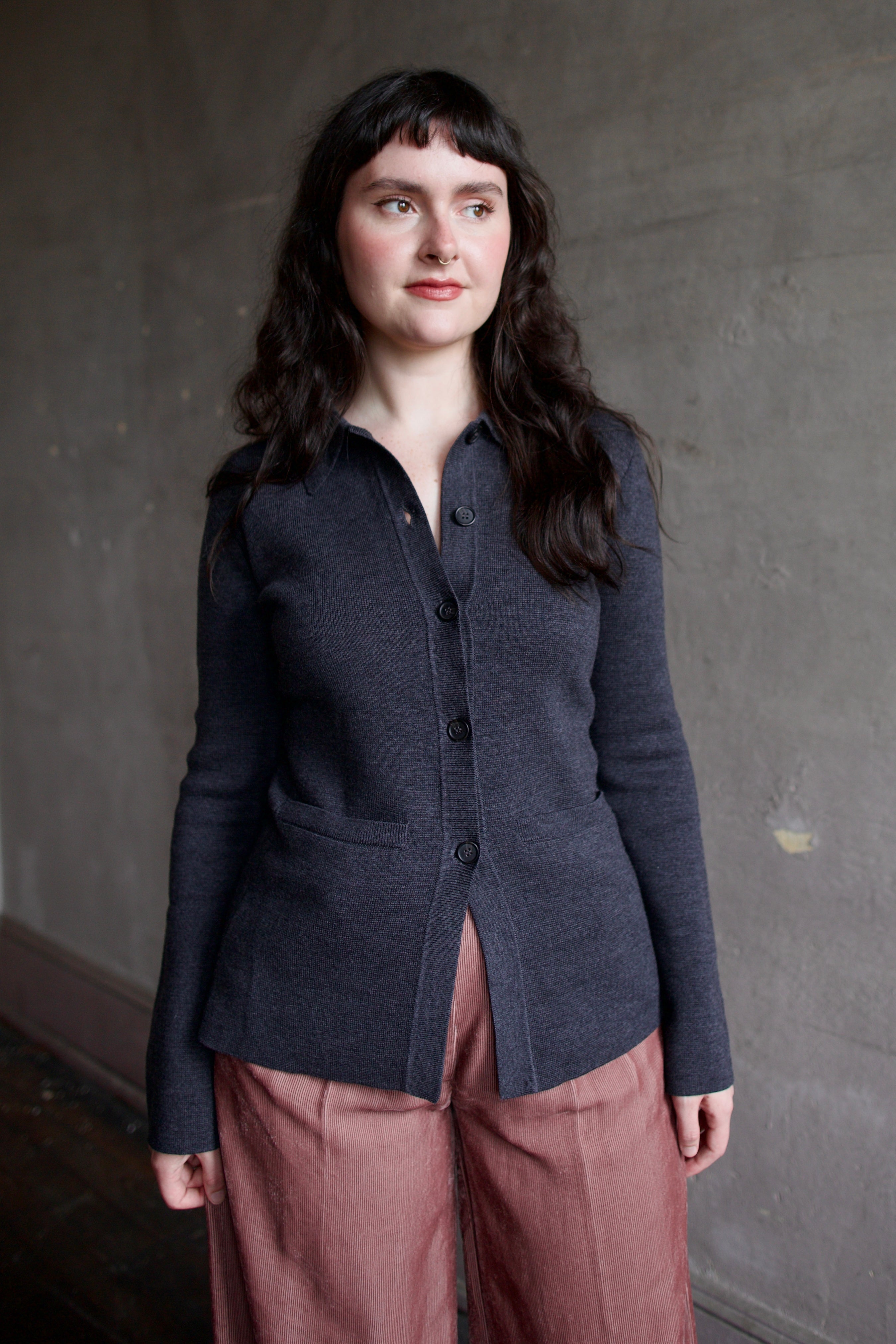 Model wearing Apiece Apart Betti dark gray knit cardigan with a button front, long sleeve, collar and front pockets