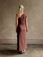 Mature woman wearing Apiece Apart brown comfy jersey cotton maxi dress one shoulder twist tie waist stretch