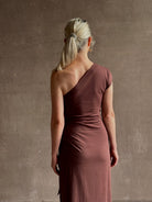 Mature woman wearing Apiece Apart brown comfy jersey cotton maxi dress one shoulder twist tie waist stretch