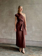 Mature woman wearing Apiece Apart brown comfy jersey cotton maxi dress one shoulder twist tie waist stretch