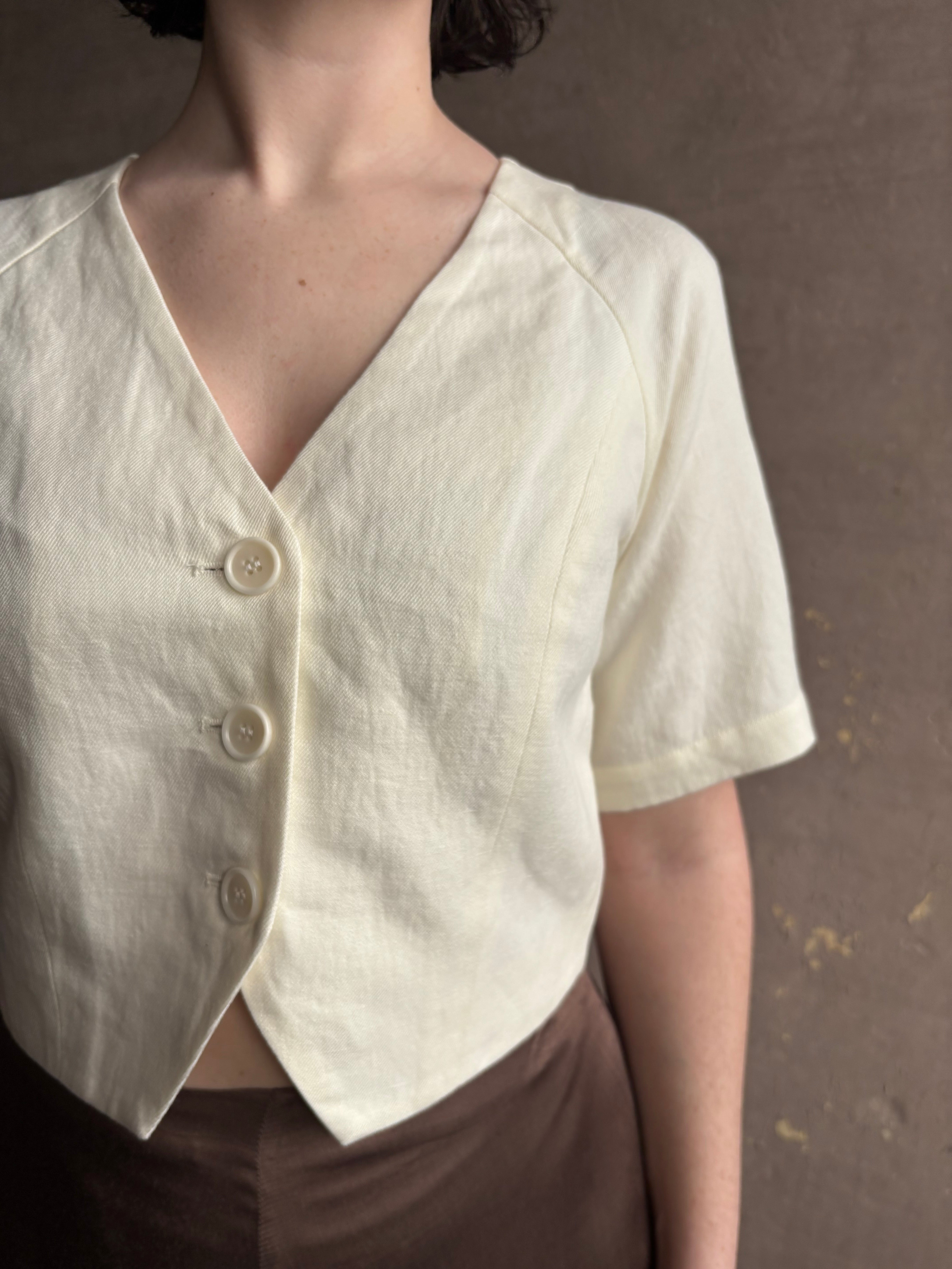 Woman wearing an elevated cream Lia designer Crop Top from Apiece Apart with short sleeves and v- neck