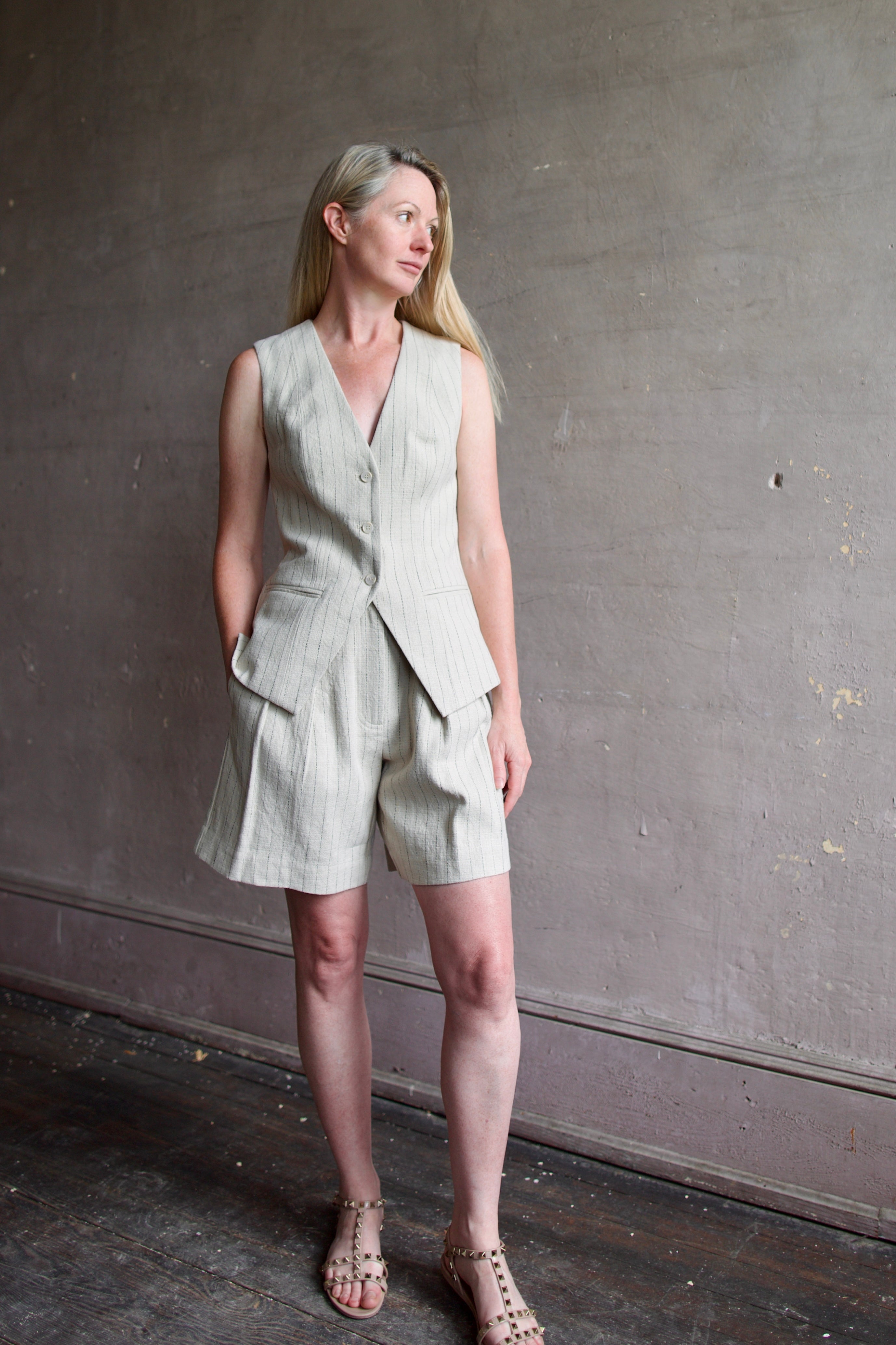 Mature woman wearing luxury brand Apiece Apart Helena Vest and Linaza Shorts in linen with expert sustainable craftsmanship, refined tailoring and long inseam