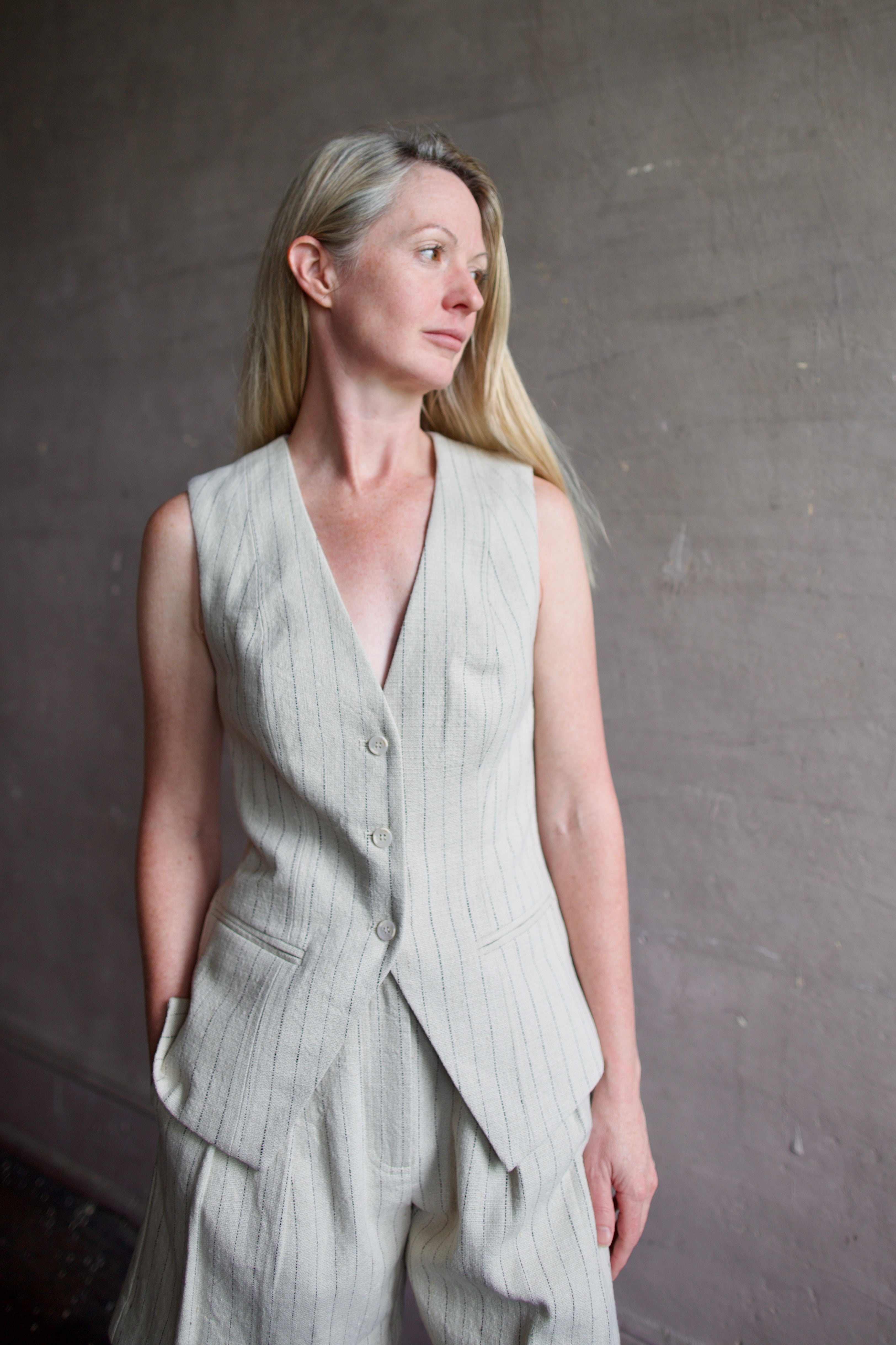 Mature woman wearing luxury brand Apiece Apart Helena Vest and Linaza Shorts in linen with expert sustainable craftsmanship, refined tailoring and long inseam
