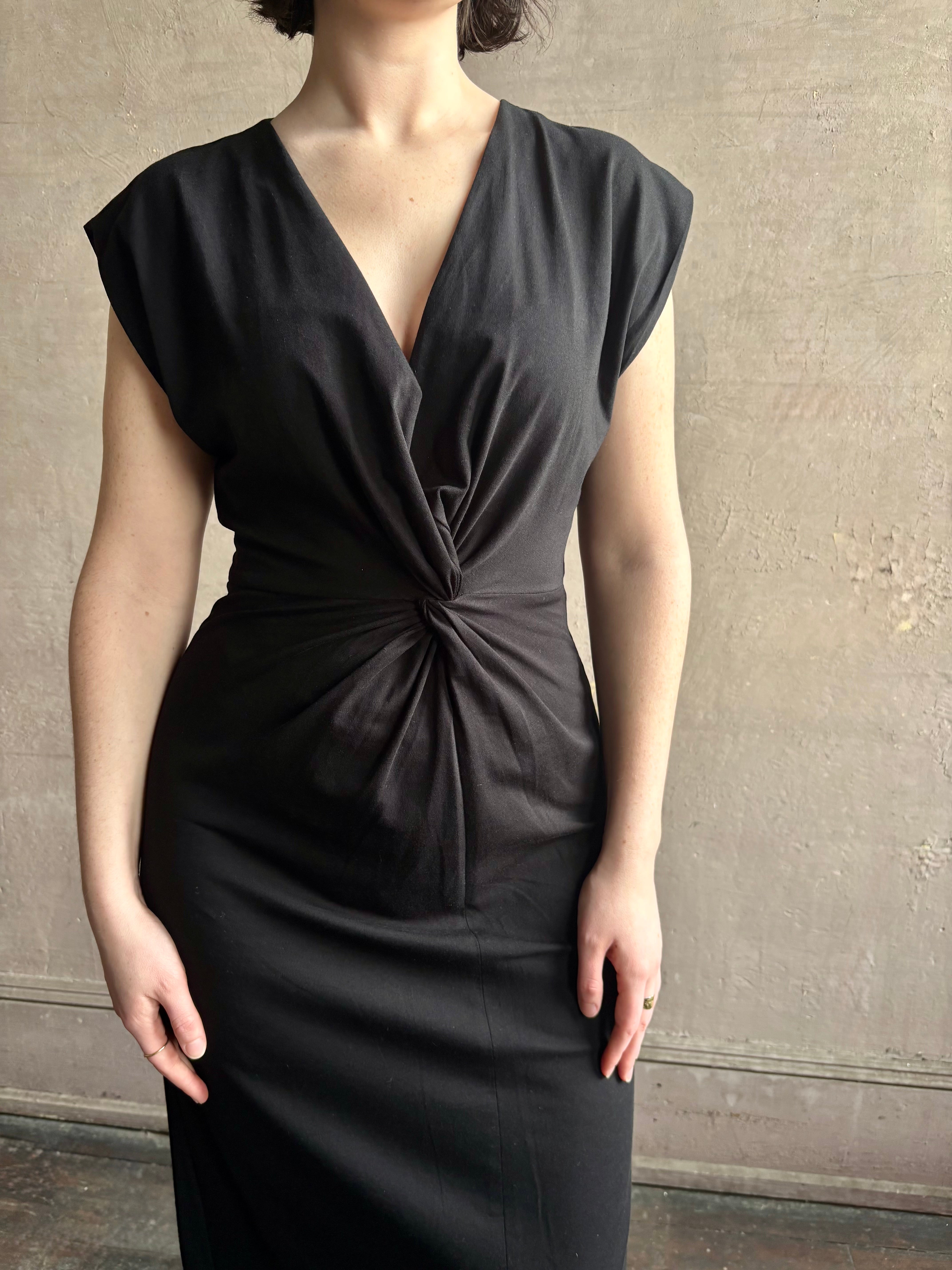 Woman wearing a timeless Twist Front Column Dress from Apiece Apart in a comfortable black cotton jersey midi that can transition day to night