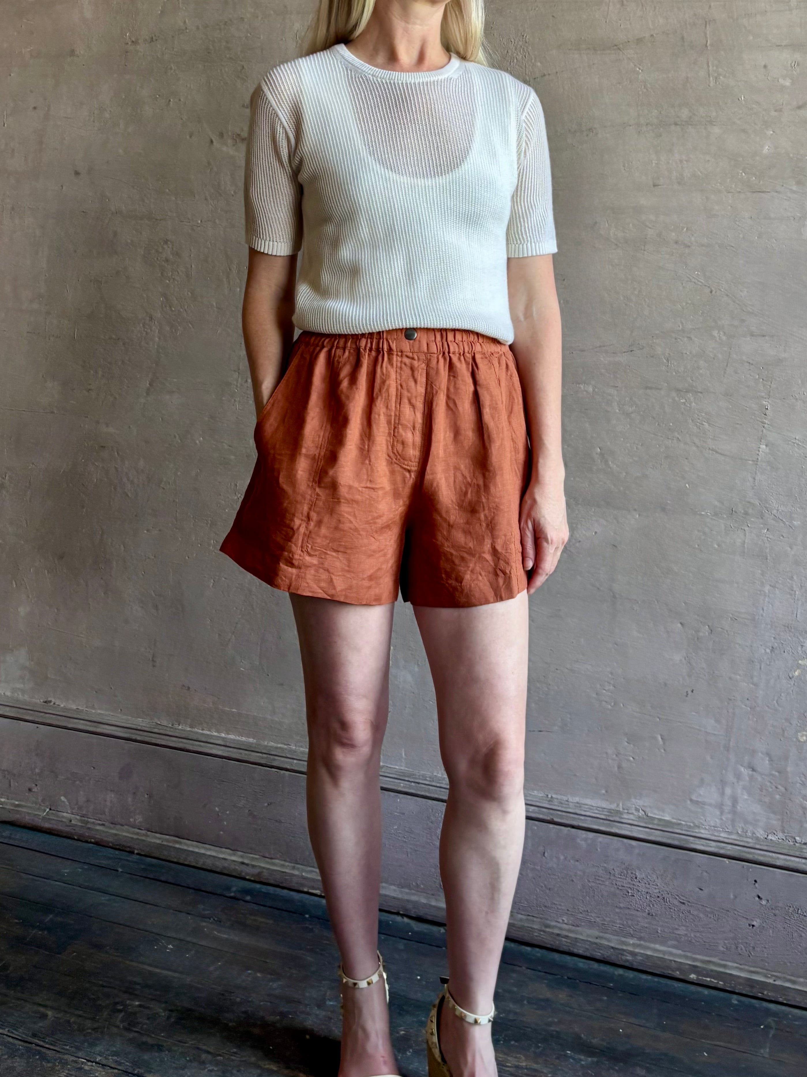 Mature woman wearing the Mar Short from Apiece Apart rendered in a rust hue and crafted from 100% linen with an adjustable elastic waistband and pockets
