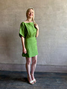 Mature woman wearing the effortlessly  Sigrun Mini summer Dress from Apiece Apart rendered in 100% linen with a boat neck, loose half sleeves and blouson style