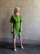 Mature woman wearing the effortlessly  Sigrun Mini summer Dress from Apiece Apart rendered in 100% linen with a boat neck, loose half sleeves and blouson style