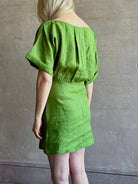 Mature woman wearing the effortlessly  Sigrun Mini summer Dress from Apiece Apart rendered in 100% linen with a boat neck, loose half sleeves and blouson style