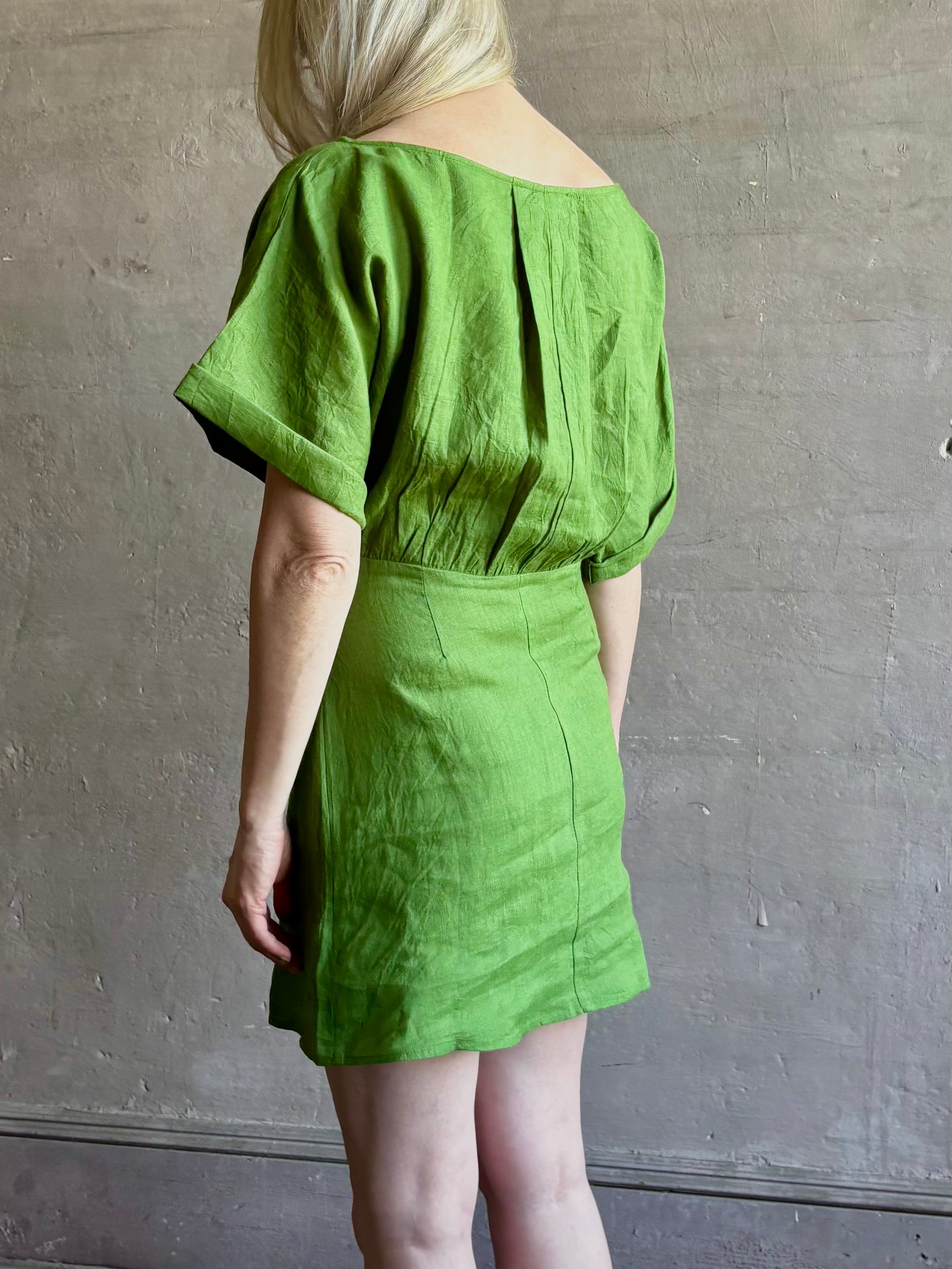 Mature woman wearing the effortlessly  Sigrun Mini summer Dress from Apiece Apart rendered in 100% linen with a boat neck, loose half sleeves and blouson style