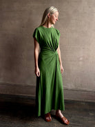 Mature woman wearing Volta Twist maxi Dress from Apiece Apart in a comfy green organic cotton jersey with short sleeves and crew neck
