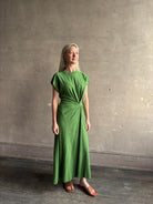 Mature woman wearing Volta Twist maxi Dress from Apiece Apart in a comfy green organic cotton jersey with short sleeves and crew neck