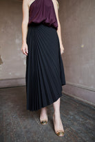 Model wearing a black pleated wool skirt and elevated date night purple top by ALC