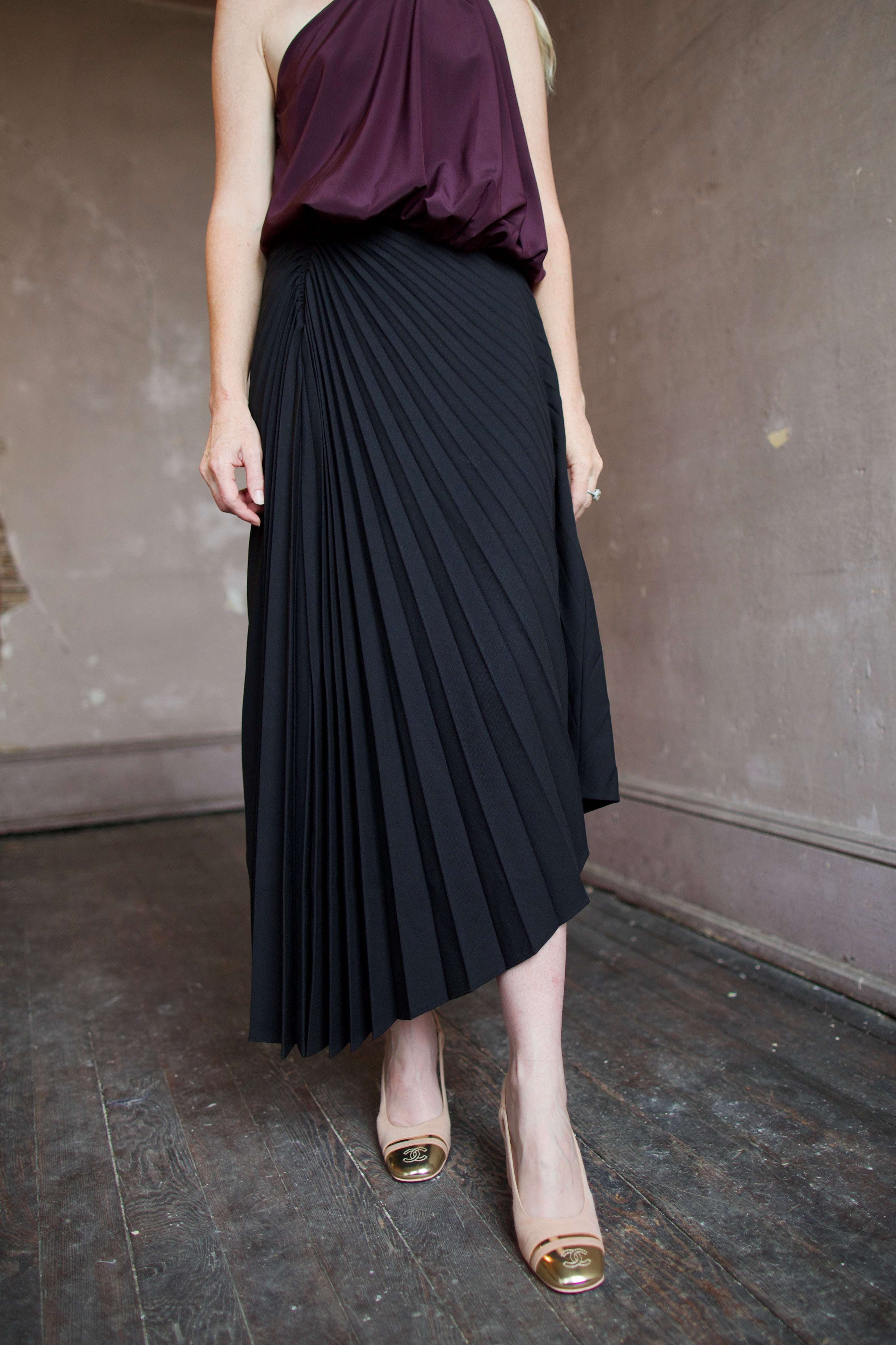 Model wearing a black pleated wool skirt and elevated date night purple top by ALC