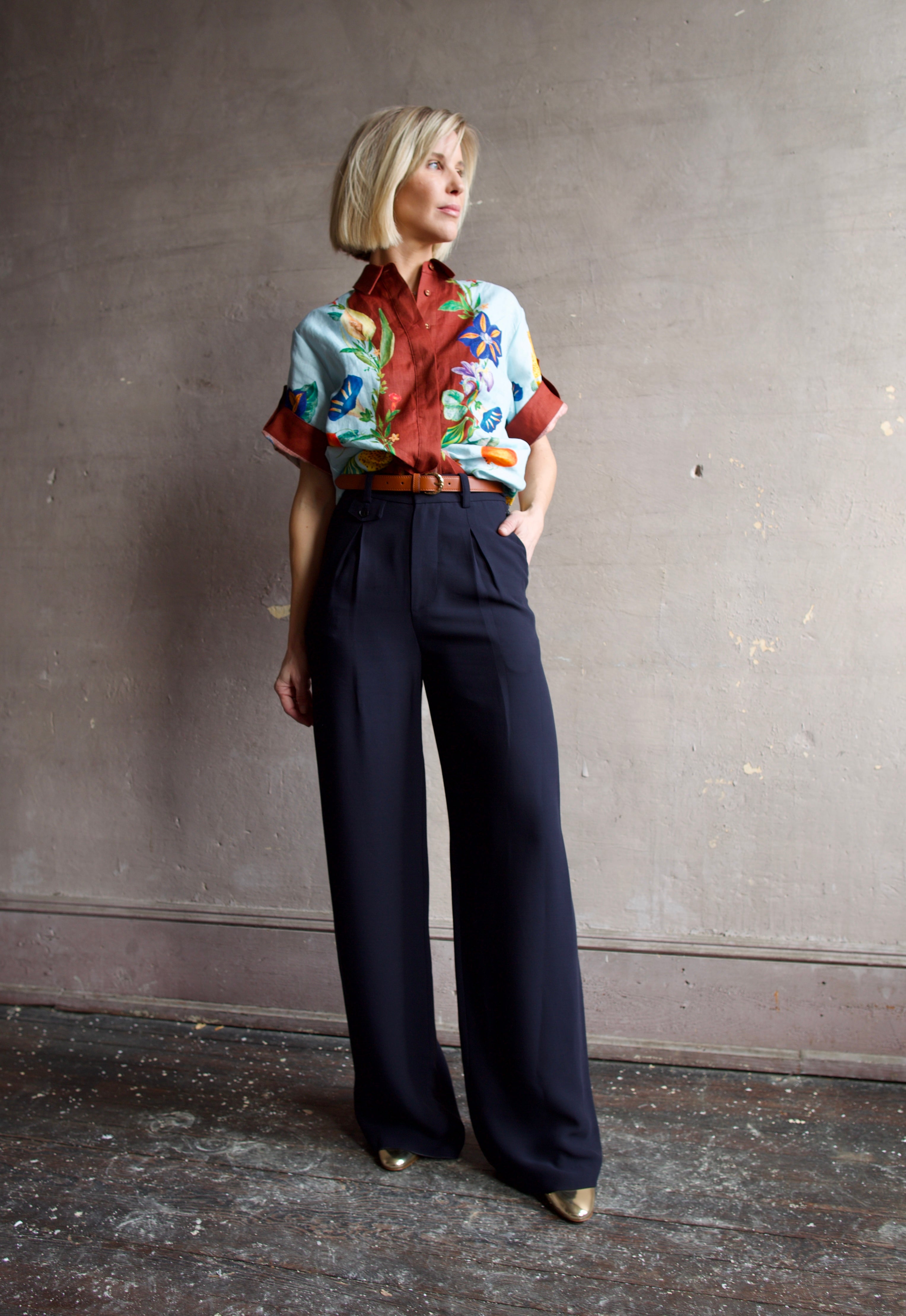 Image of a woman wearing the Alemais Dahlia top, Ulla Johnson Gia Belt, Elise Ruffle Heels and Apiece Apart Cara Wide leg trousers. 