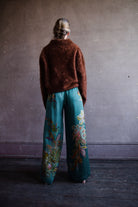 Image featuring a woman wearing the silk Franca pants by Alemais with a drawstring waist and wide leg paisley print in turquoise.