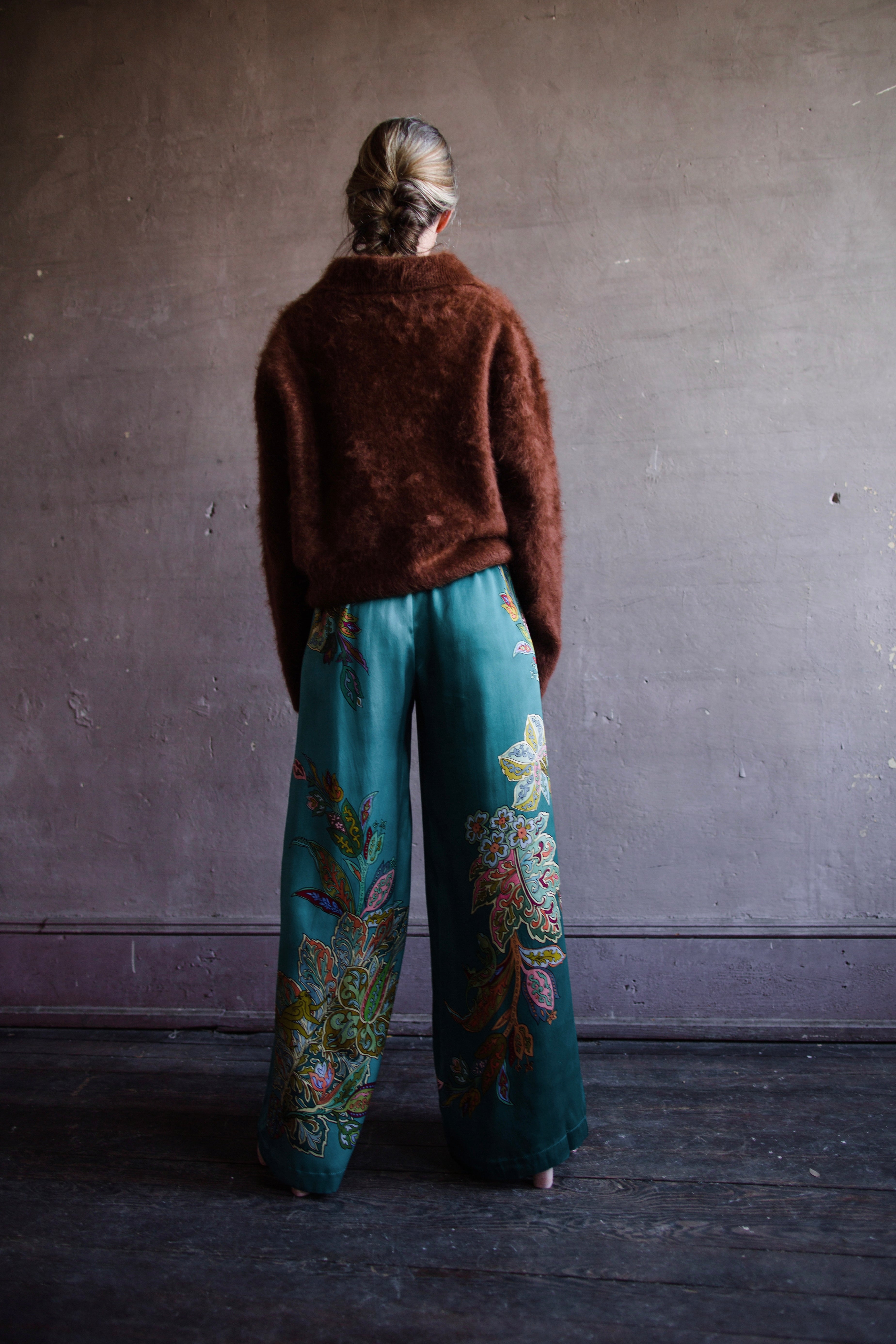 Image featuring a woman wearing the silk Franca pants by Alemais with a drawstring waist and wide leg paisley print in turquoise.