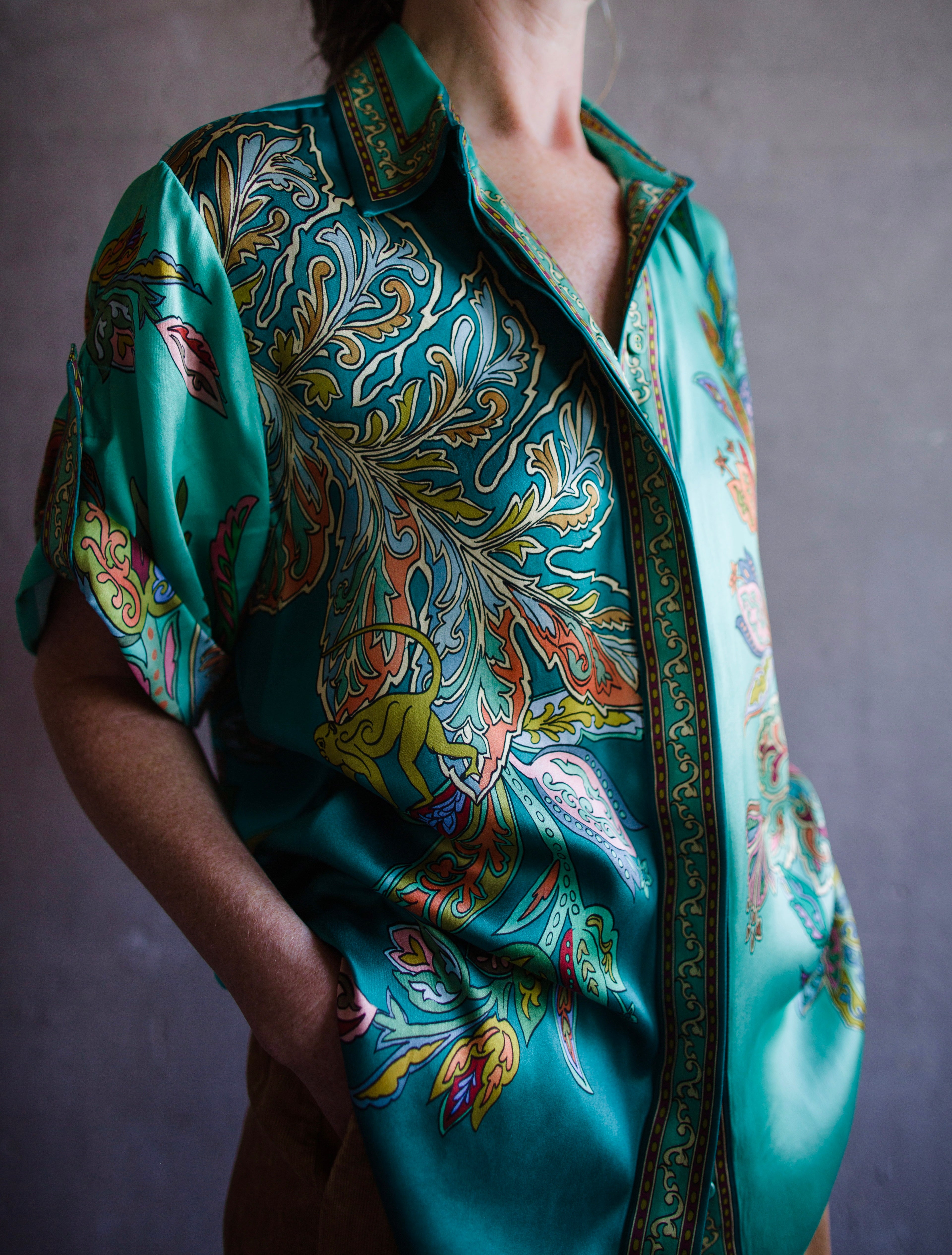 Image featuring a woman wearing the silk Franca button up top by Alemais with a rolled sleeve and relaxed fit in turquoise.