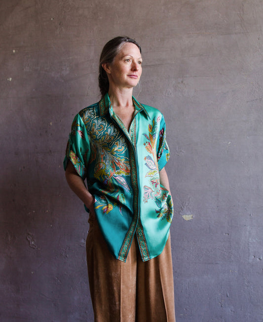 Image featuring a woman wearing the silk Franca button up top by Alemais with a rolled sleeve and relaxed fit in turquoise.