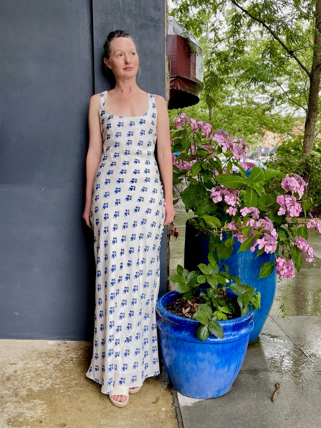 Image featuring a woman wearing the Adele maxi sheath dress by Alix of Bohemia with a cotton and silk fabrication, a scoop neckline and a bias cut in White with Blue flowers throughout.