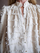 Image featuring a woman wearing the Alix of Bohemia Ana Snow Feather Shirt with a button front,  puff sleeves, a boxy fit and intricate texture throughout.