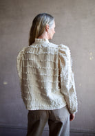 Image featuring a woman wearing the Alix of Bohemia Ana Snow Feather Shirt with a button front,  puff sleeves, a boxy fit and intricate texture throughout.