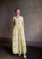 Image featuring a woman wearing the Autumn Embroidered dress by Alix of Bohemia with spaghetti straps that lace up the back, a tailored bodice and allover embroidery in yellow.