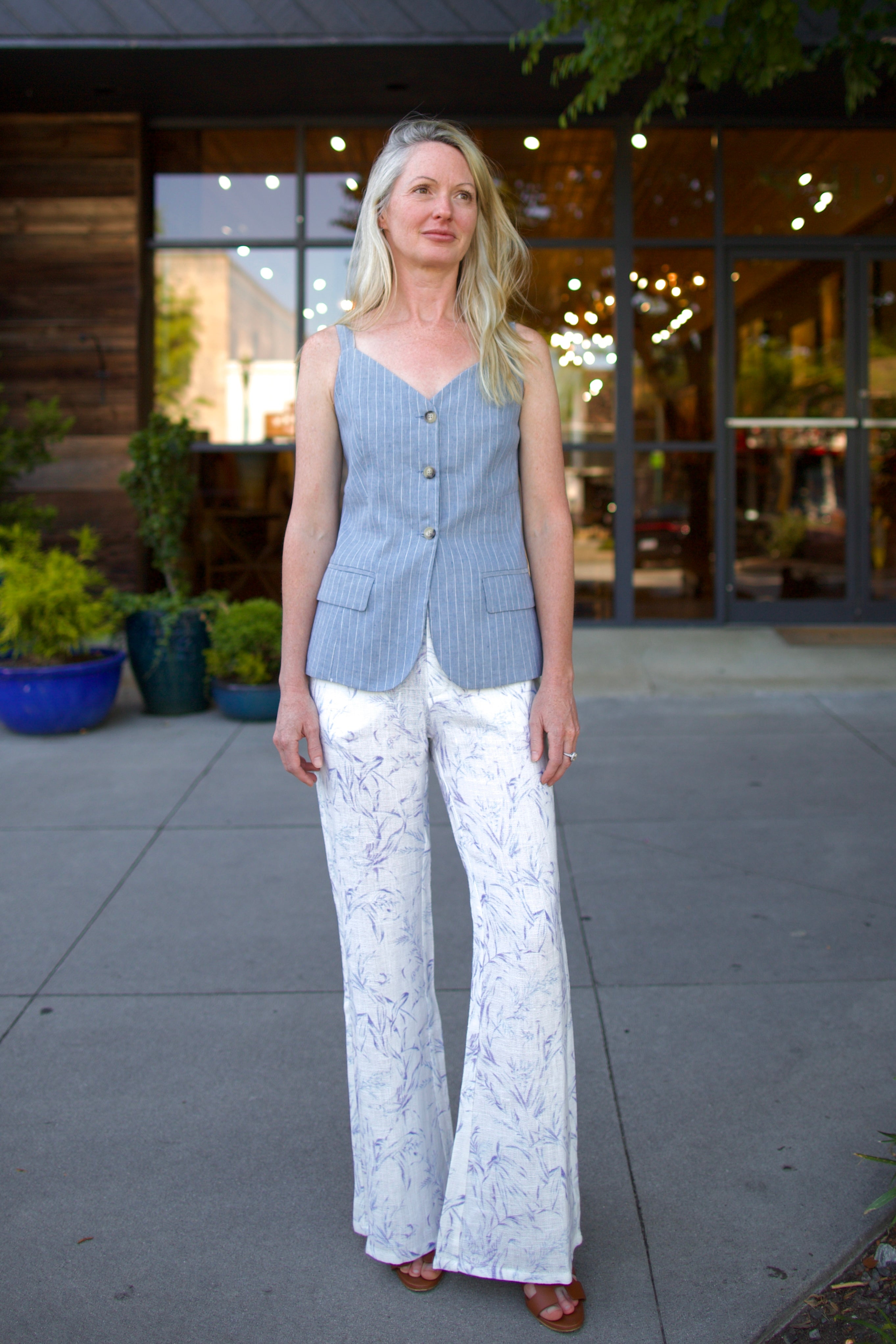 Woman wearing luxury designer Alix of Bohemia bunny toile linen trousers in white with blue print flare high rise