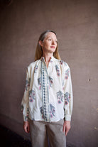 Image featuring a woman wearing the Alix of Bohemia Kiki Mirabillis top with a button front, full sleeve and a blue & pink floral block print on a white wool shirt.