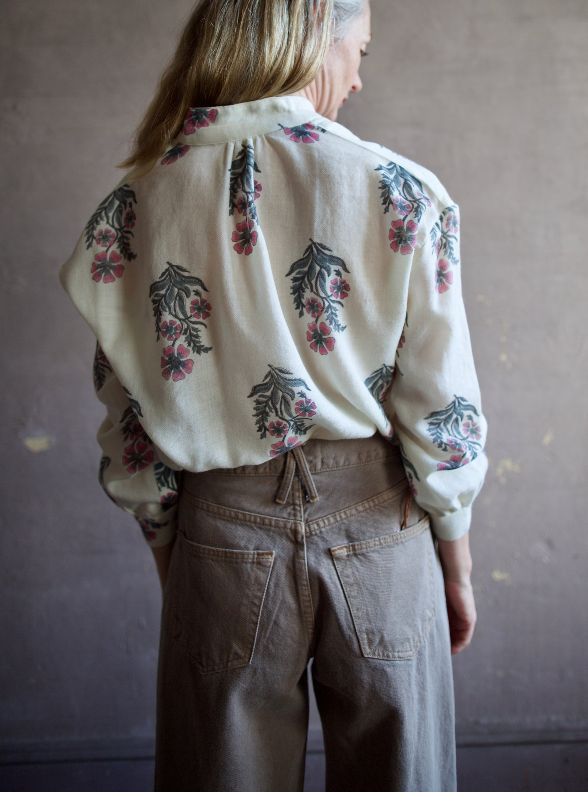 Image featuring a woman wearing the Alix of Bohemia Kiki Mirabillis top with a button front, full sleeve and a blue & pink floral block print on a white wool shirt.