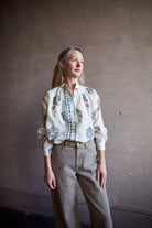 Image featuring a woman wearing the Alix of Bohemia Kiki Mirabillis top with a button front, full sleeve and a blue & pink floral block print on a white wool shirt.