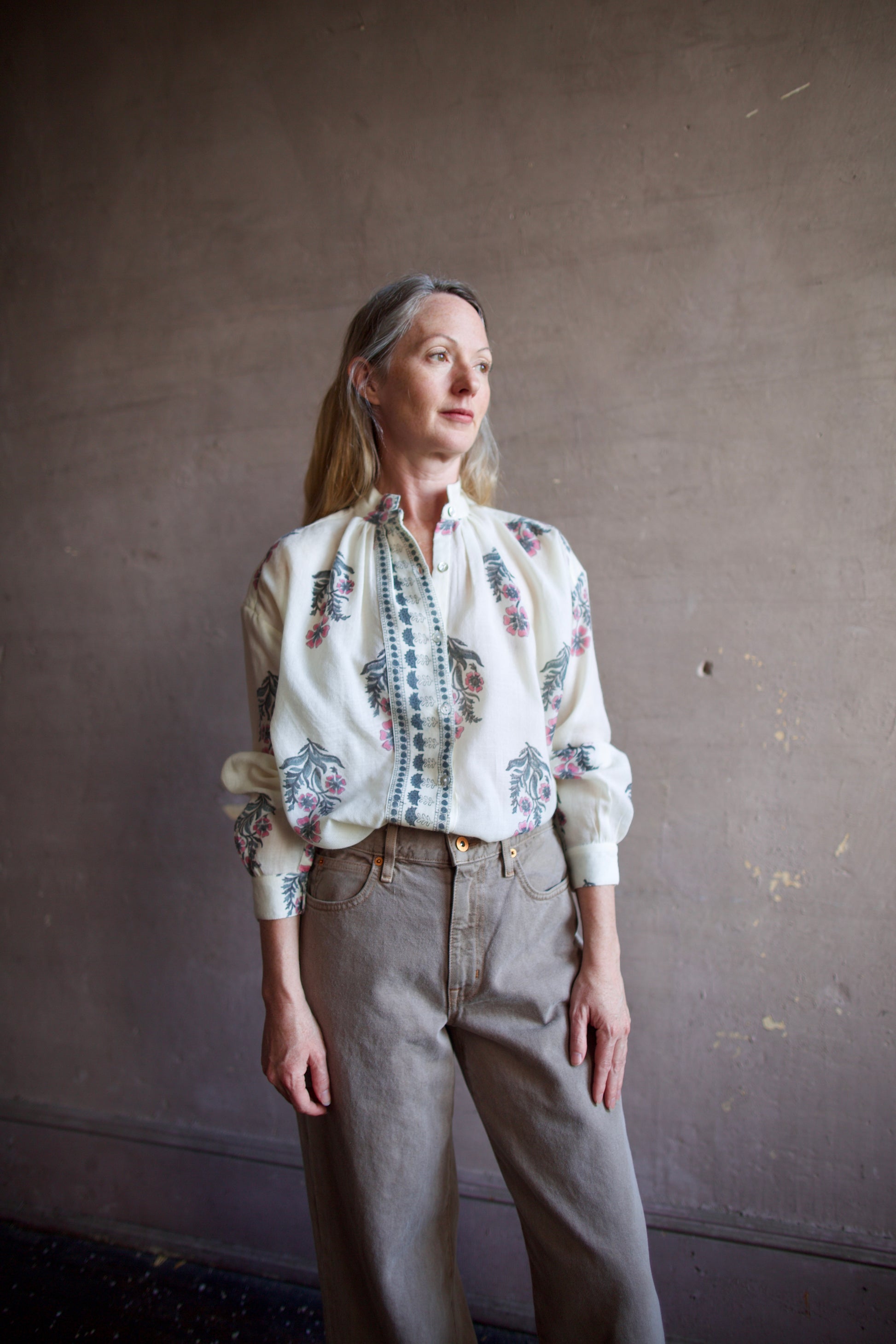 Image featuring a woman wearing the Alix of Bohemia Kiki Mirabillis top with a button front, full sleeve and a blue & pink floral block print on a white wool shirt.