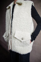 Image featuring a woman wearing the Alix of Bohemia Mickey Suri wool vest knitted with Italian alpaca wool in cream with front pockets with flaps and integral side seam pockets.