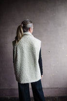 Image featuring a woman wearing the Alix of Bohemia Mickey Suri wool vest knitted with Italian alpaca wool in cream with front pockets with flaps and integral side seam pockets.