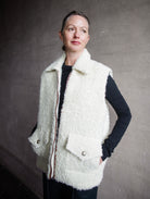 Image featuring a woman wearing the Alix of Bohemia Mickey Suri wool vest knitted with Italian alpaca wool in cream with front pockets with flaps and integral side seam pockets.