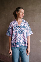 Image featuring a woman wearing the Stevie Oasis cotton top by Alix of Bohemia with a button front, short sleeves and a boxy fit in a Pink and Blue bold print.