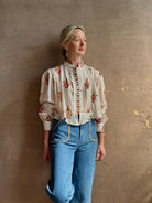 Mature woman wearing Alix of Bohemia Ryland Persimmon Flower Shirt with beautiful pin tucking and gathered waist detail at back, long sleeves, mandarin collar, and cropped top