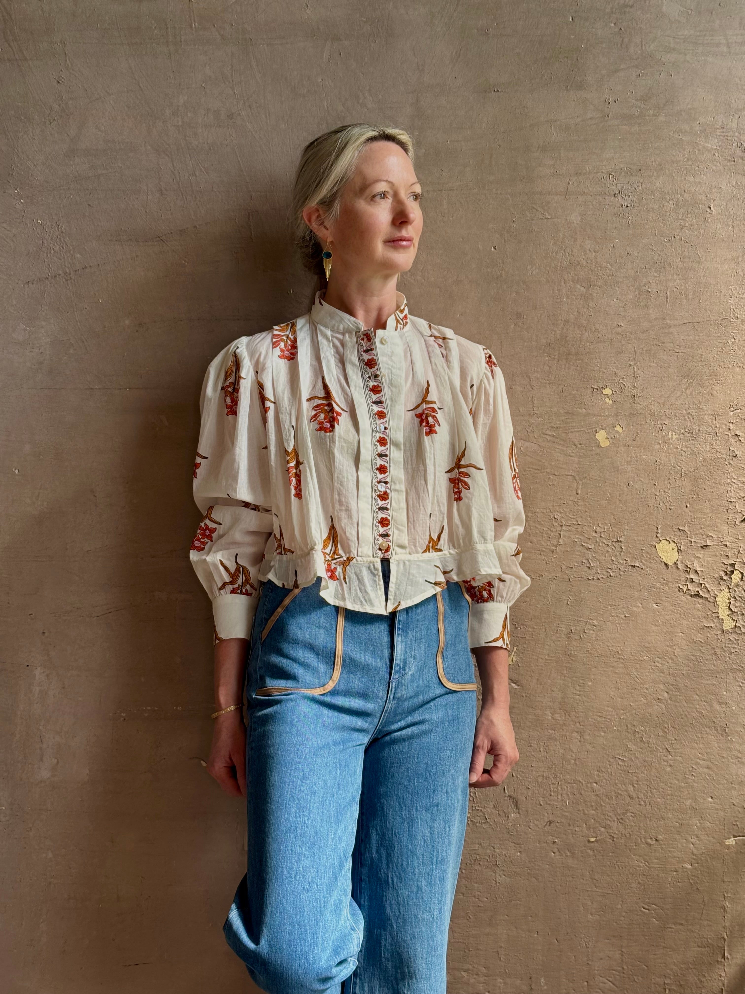 Mature woman wearing Alix of Bohemia Ryland Persimmon Flower Shirt with beautiful pin tucking and gathered waist detail at back, long sleeves, mandarin collar, and cropped top