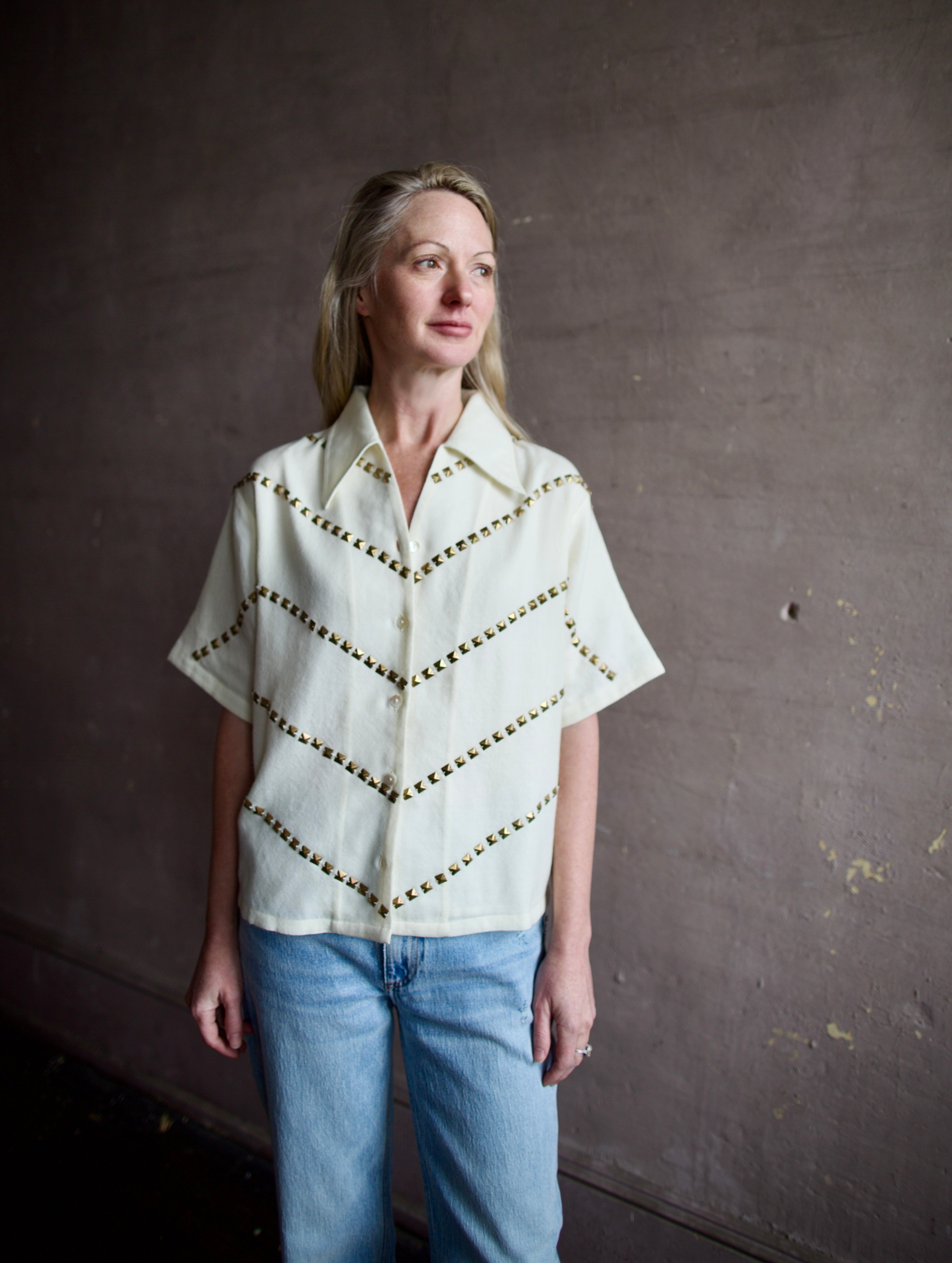 Mature woman wearing Alix of Bohemia Stevie Studded top with button front short sleeves and a collar metal embellishments in V design across entire front