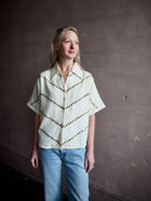 Mature woman wearing Alix of Bohemia Stevie Studded top with button front short sleeves and a collar metal embellishments in V design across entire front