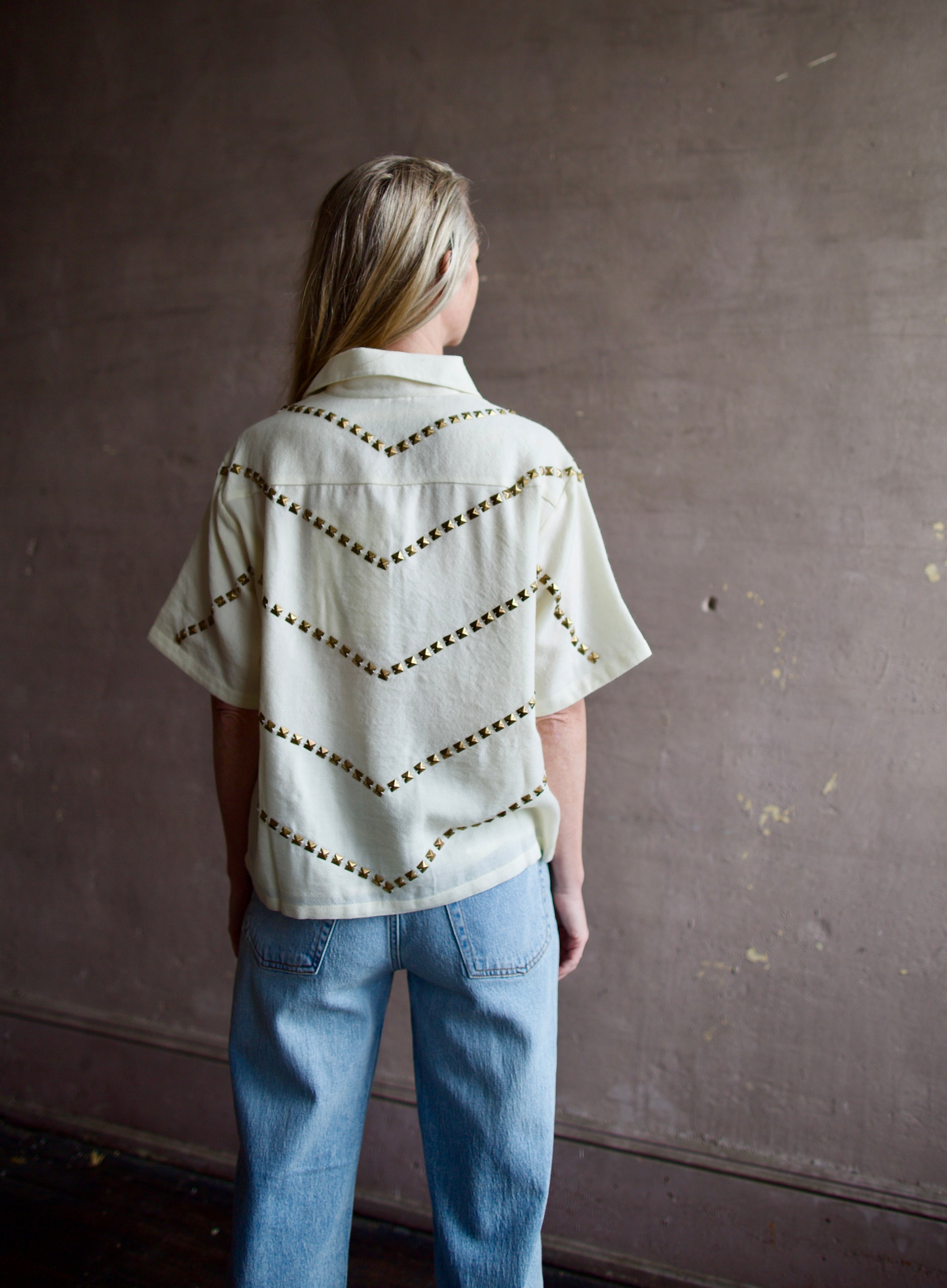Mature woman wearing Alix of Bohemia Stevie Studded top with button front short sleeves and a collar metal embellishments in V design across entire back