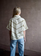Mature woman wearing Alix of Bohemia Stevie Studded top with button front short sleeves and a collar metal embellishments in V design across entire back