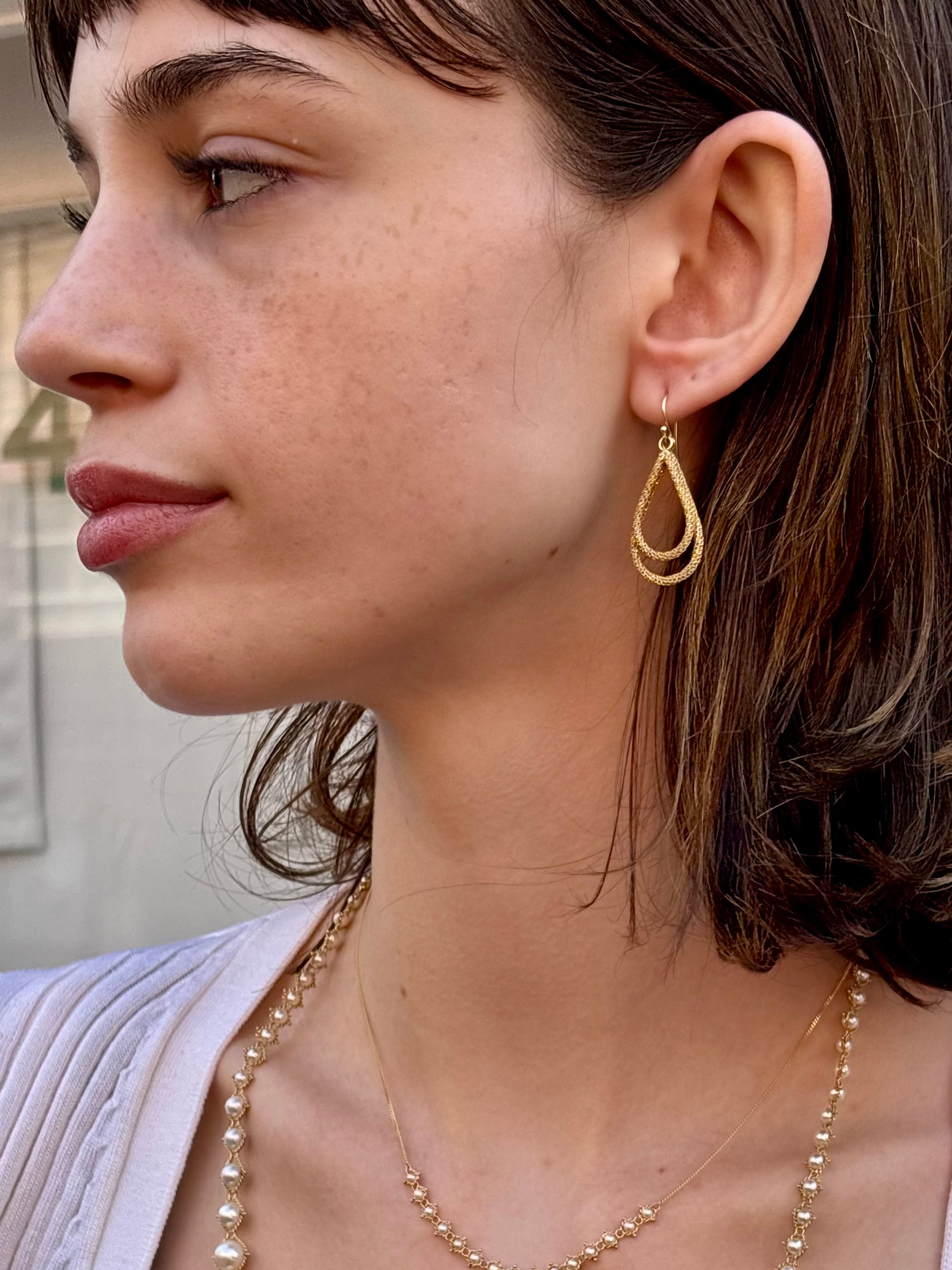Woman wearing luxury designer Amali double Teardrop Stardust 18k yellow gold Earrings handmade in USA fine jewelry