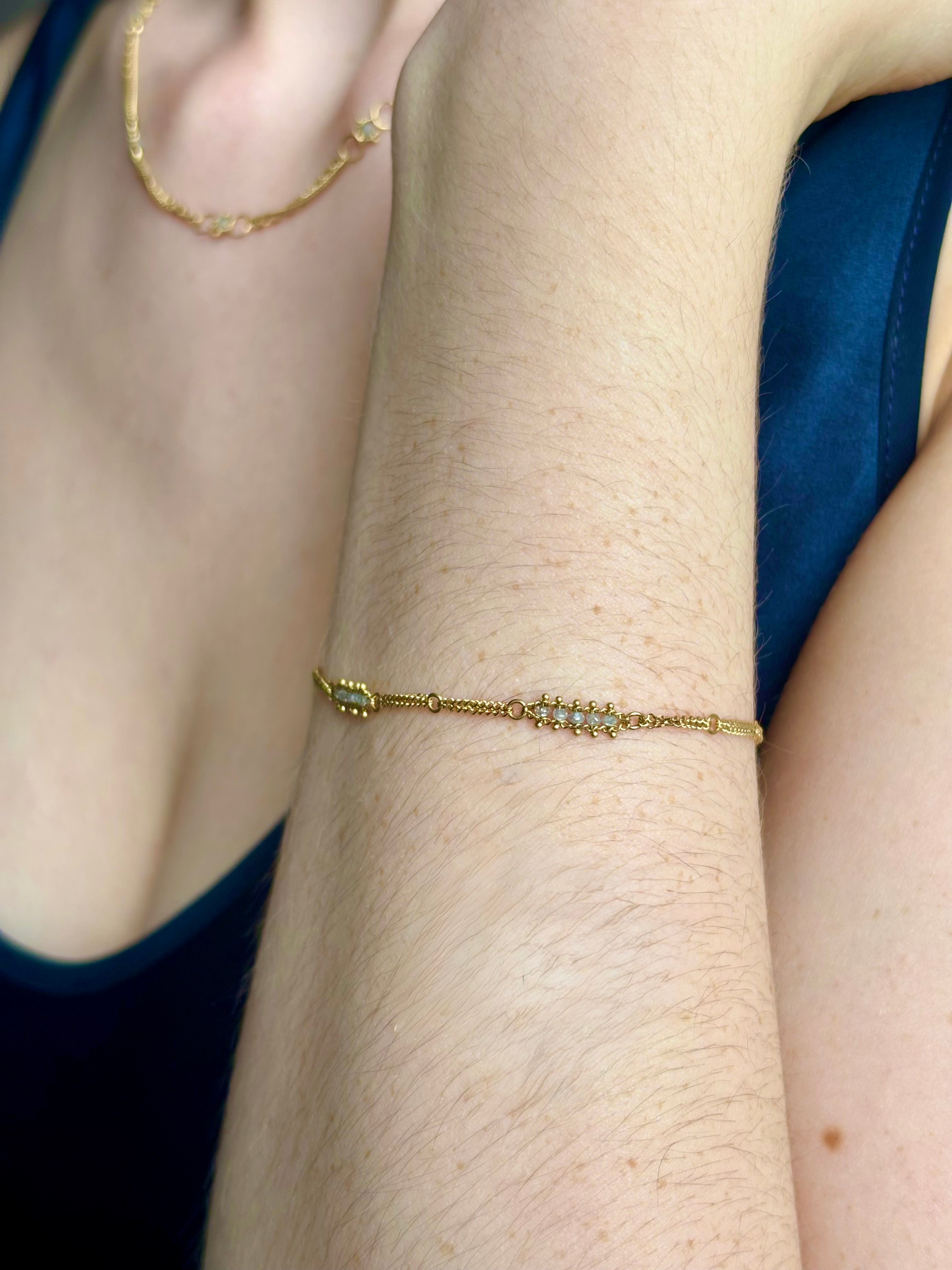 Woman wearing silver diamond and yellow gold bracelet with 5 diamond groupings all the way around by US fine jewelry designer Amali. A stylish modern take on a classic